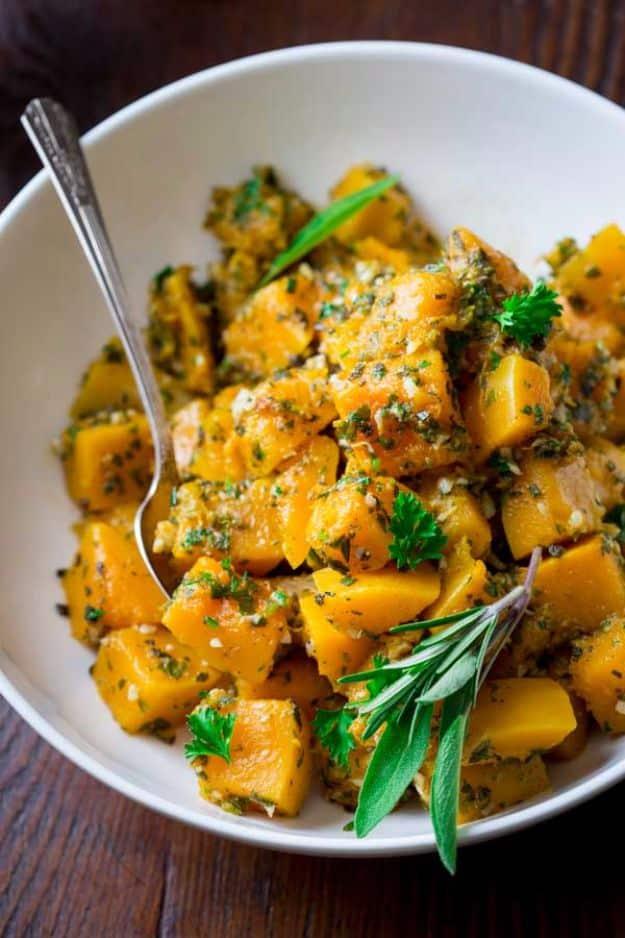 Steamed garlic herb butternut squash cubes tossed with chopped parsley, thyme and rosemary in a bowl