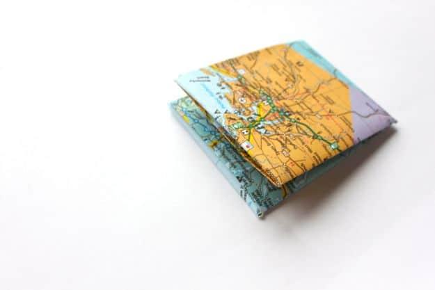 DIY paper wallet, a small wallet folded from a blue and tan road map lying closed on a plain white surface
