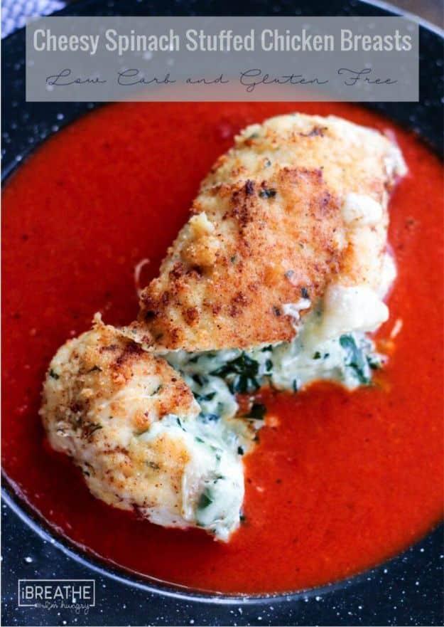 Keto cheesy spinach stuffed chicken breast in golden almond flour breading, cut open over a pool of tomato sauce