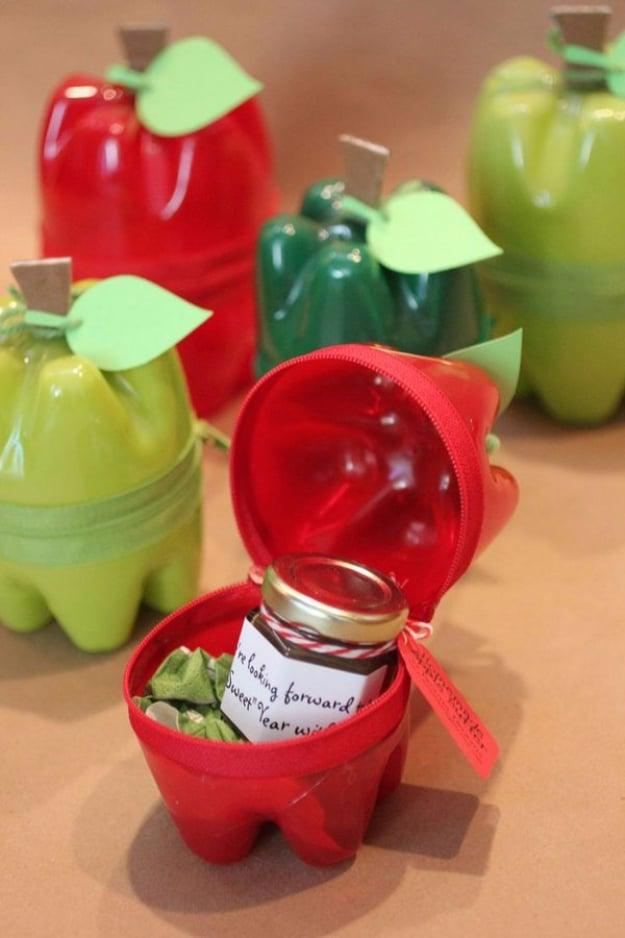 Red and green apple containers made from painted soda bottle bottoms joined with zippers, one open holding a jam jar