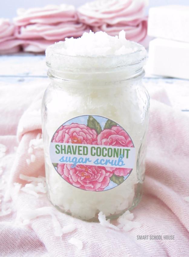 Shaved coconut sugar scrub, a white coconut scrub in a labeled mason jar resting on soft pink folded fabric