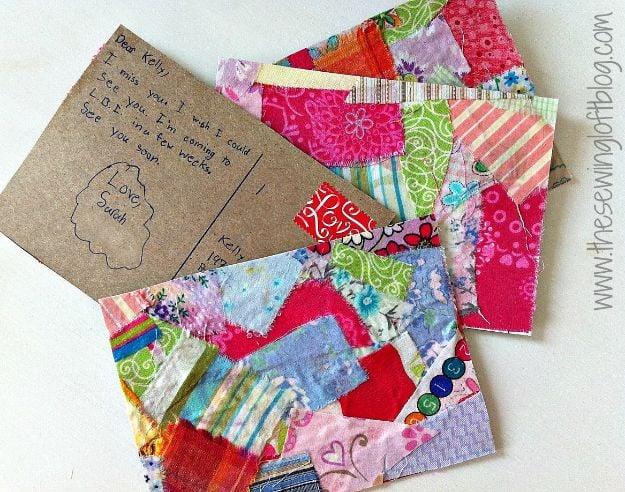 Three postcards covered in overlapping pink, red, green and blue fabric scraps beside a handwritten kraft postcard