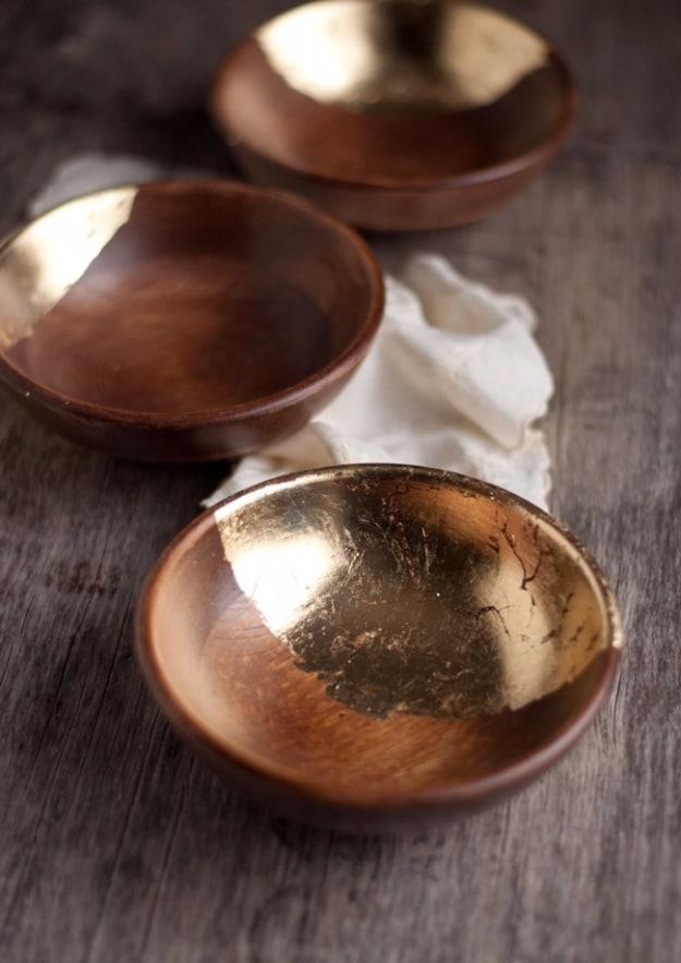 Wooden bowls with gold leaf, three dark wooden bowls with gold leaf laid inside the curve on weathered gray wood