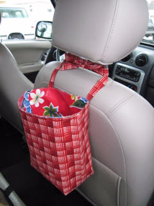 Red and white checked fabric bag with a floral lining tied to the headrest posts of a light gray car back seat