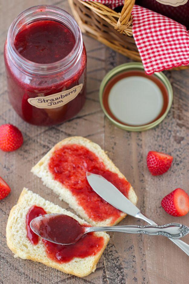 Homemade strawberry jam in glass jars, made with fresh strawberries, sugar and lemon, set beside a spoon