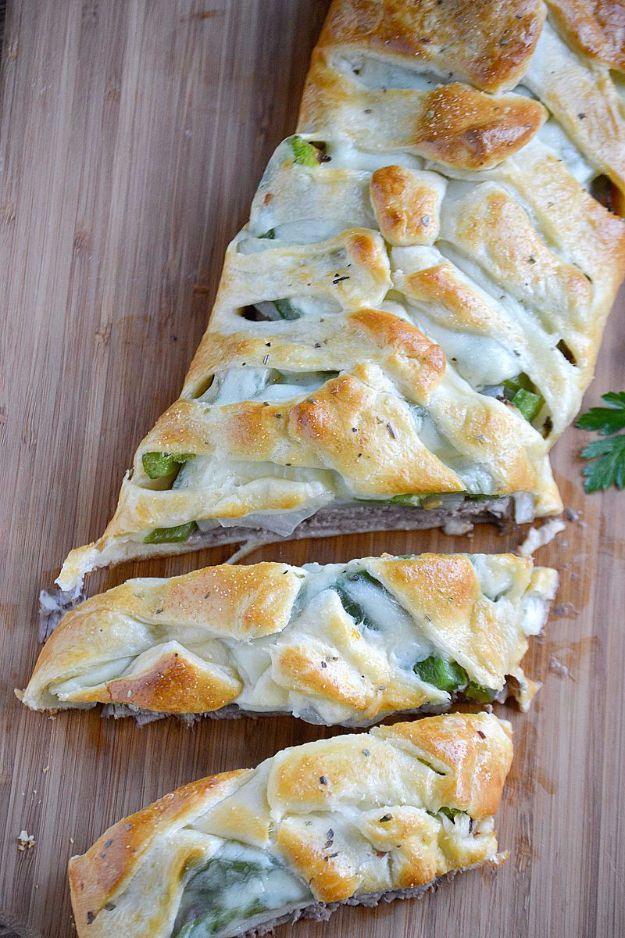 Philly cheesesteak crescent braid filled with roast beef, provolone, peppers and onions, sliced on a board