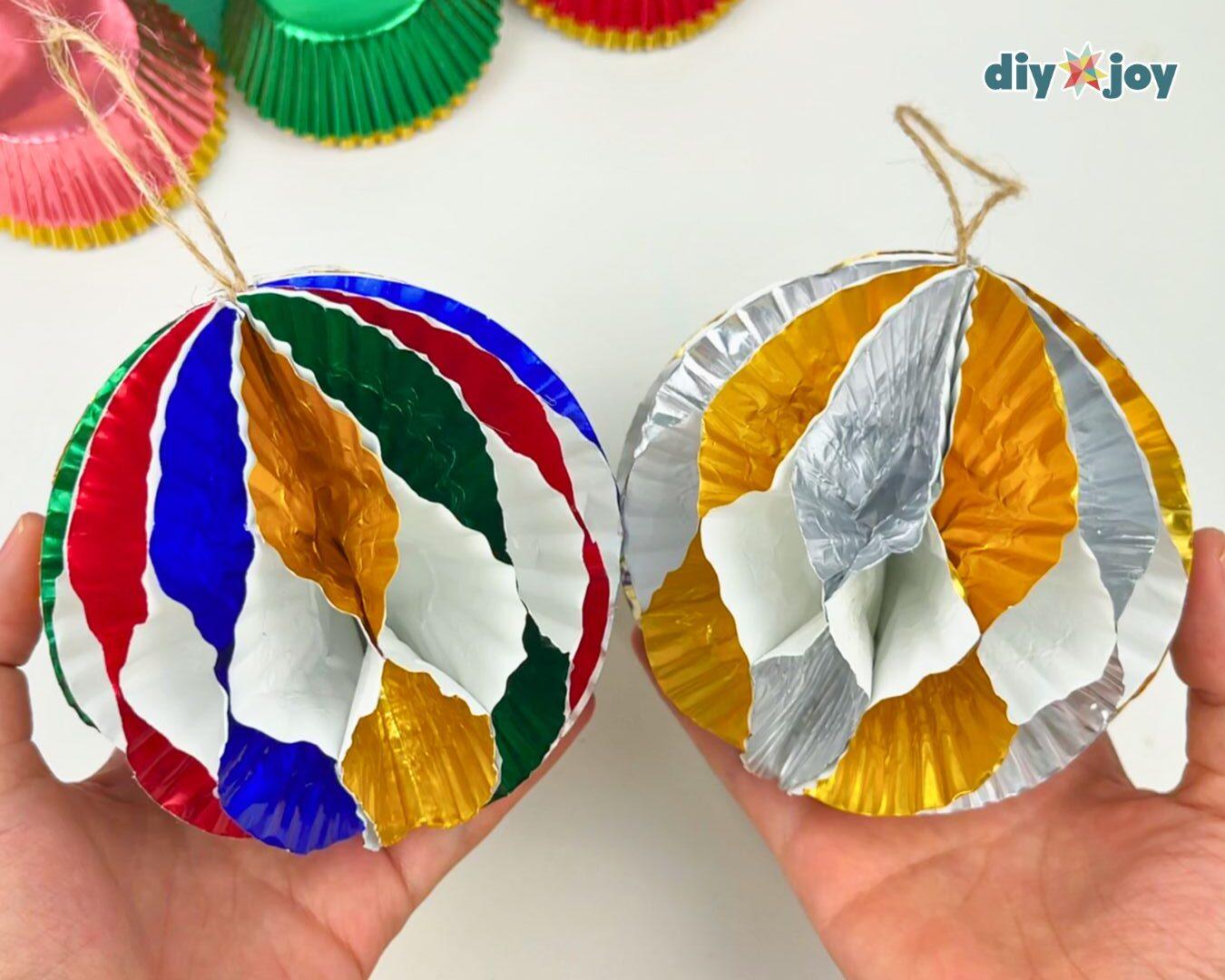 DIY Cupcake Liner Crafts - two hands each holding a finished ornament, one in red, blue, and green and one in gold and silver