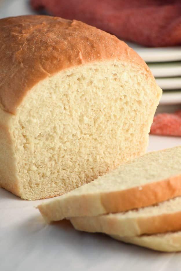 Two loaves of easy homemade white bread cooling in 9x5 pans with buttered golden tops and soft crumb