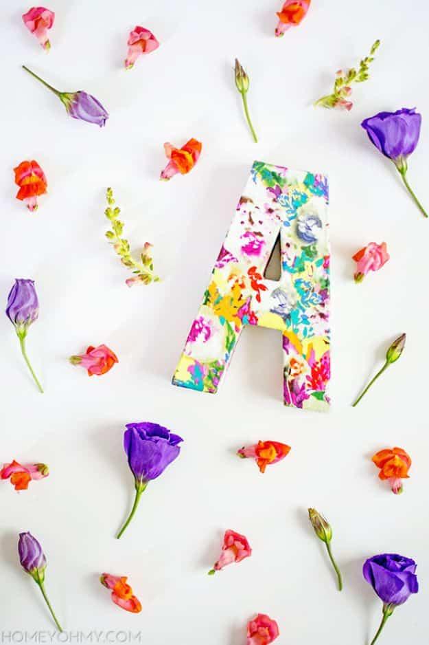 DIY floral monogram, a cardboard letter A covered in bright floral fabric, laid flat among scattered fresh blooms