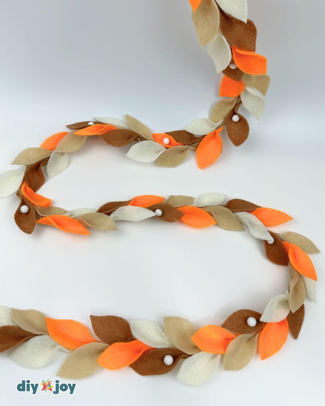 Fall garland made from felt leaves, rope, and pom-poms, an easy colorful way to decorate for the season.
