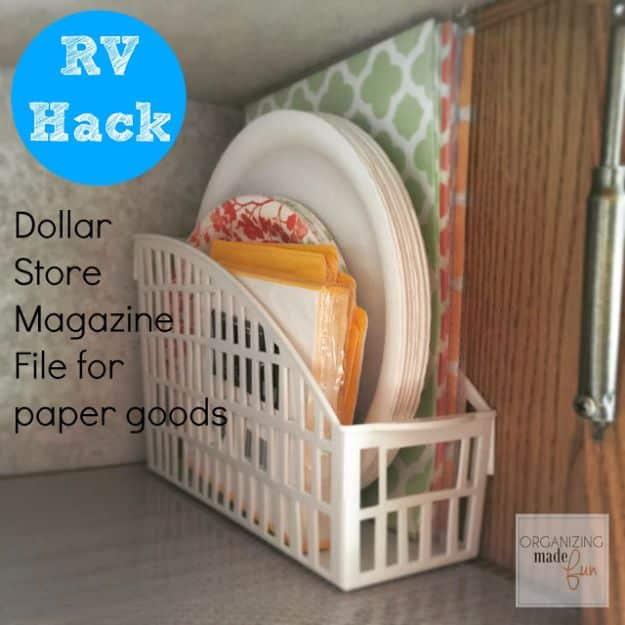 White plastic magazine file inside a cupboard holding paper plates and orange trays, under a blue RV Hack badge