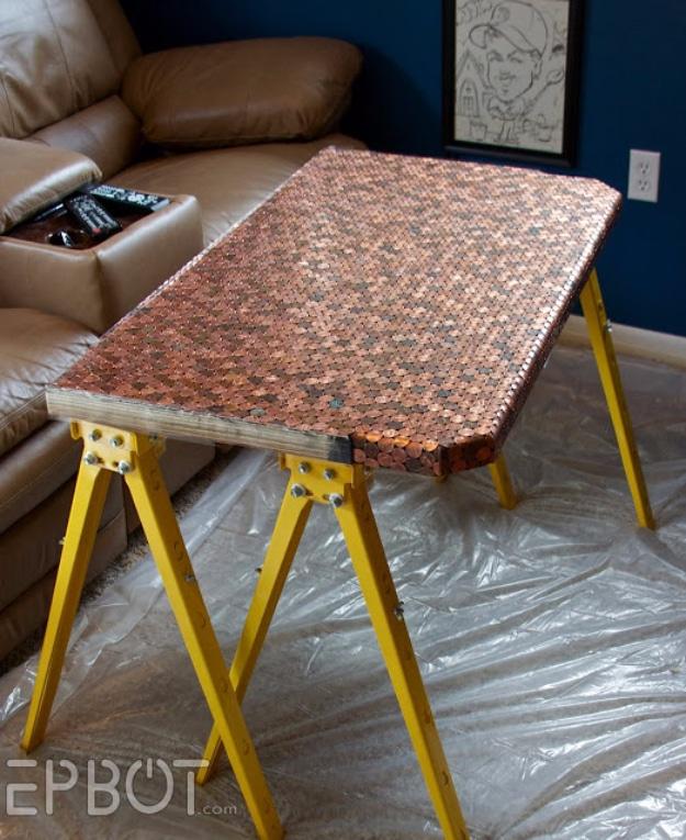 Penny desk top covered in copper coins on yellow sawhorses, plastic sheeting below, waiting for its epoxy pour