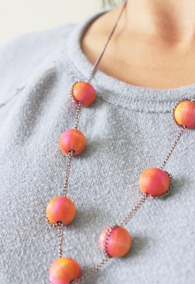 Sharpie beaded necklace, a long chain necklace of round wooden beads blended orange to pink on a grey sweatshirt