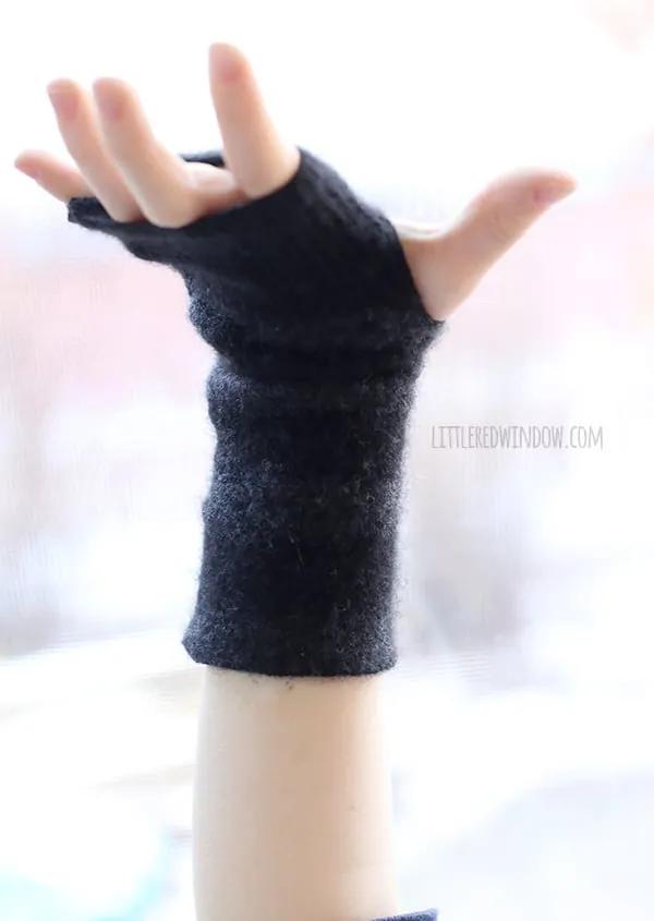 Charcoal felted cashmere fingerless gloves worn on a pair of hands against a white background, thumb openings visible