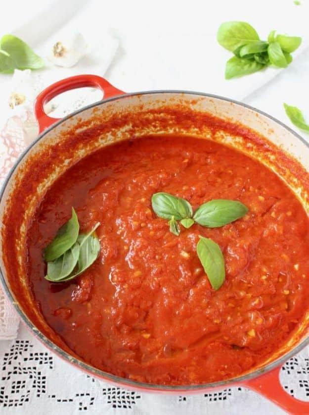 Homemade Italian marinara sauce simmering in a heavy pot with crushed San Marzano tomatoes and basil