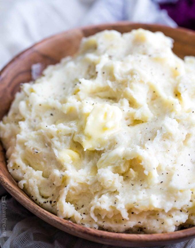 Creamy mashed potatoes with butter and pepper in a wooden bowl as a finished crockpot Thanksgiving side dish
