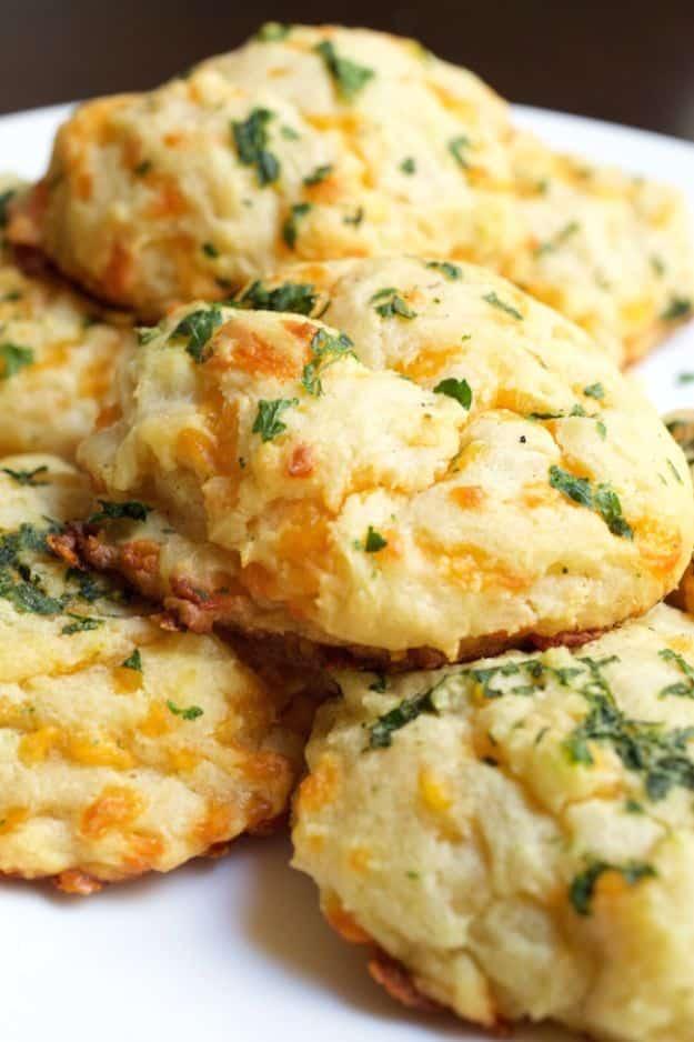 Pile of golden copycat cheddar bay biscuits flecked with parsley and melted sharp cheese on a white plate