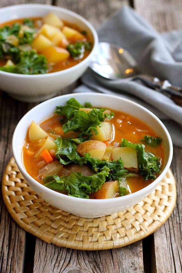Vegan potato soup with beans and kale in white bowls with potato chunks, kale leaves and carrot slices