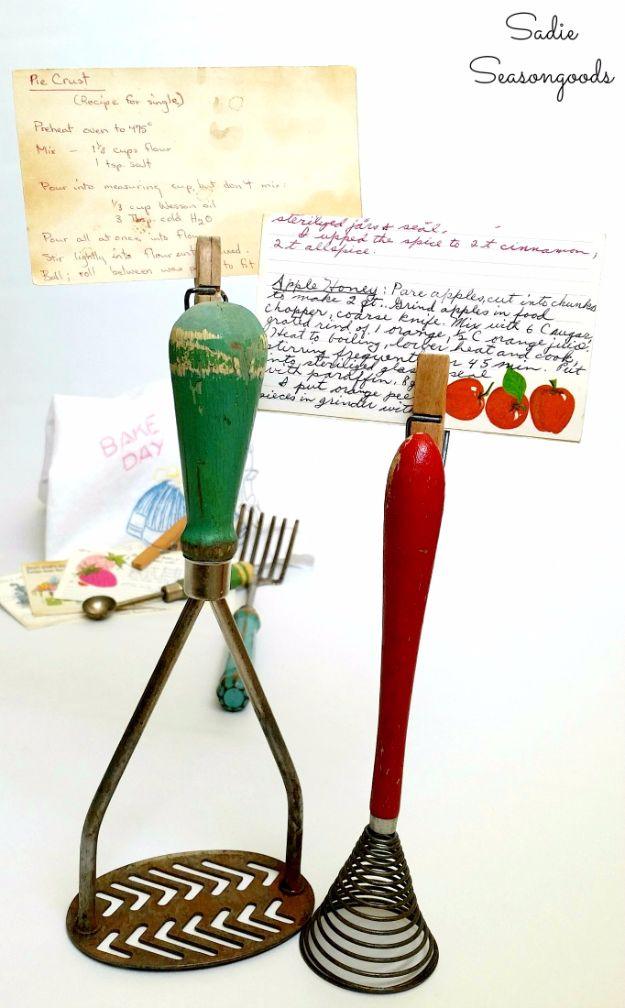 A vintage eggbeater turned upright to grip a handwritten recipe card, country crafts made from old kitchen finds