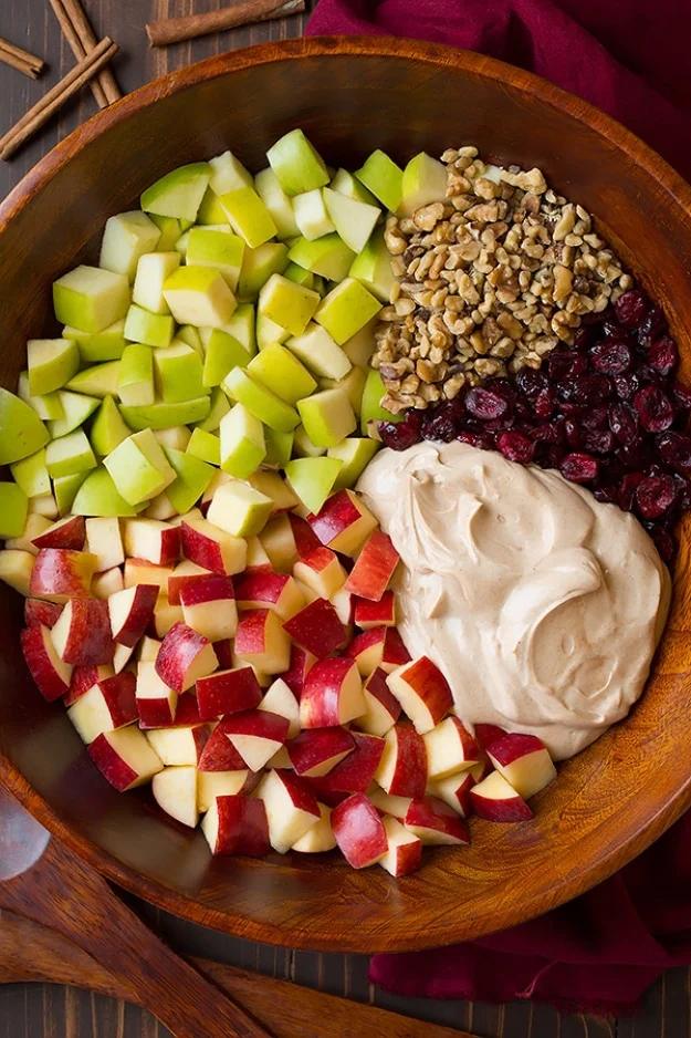 Creamy cinnamon apple and walnut fruit salad with dried cranberries served in a large white serving bowl