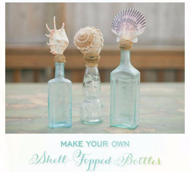 DIY shell topped bottles, three pale blue glass bottles with a spiral, a snail and a striped scallop set in the necks