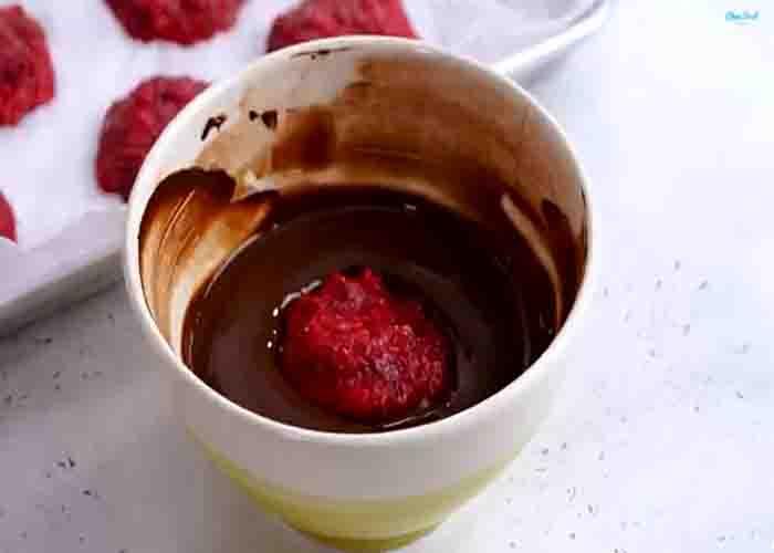 Coating the frozen raspberry with melted chocolate