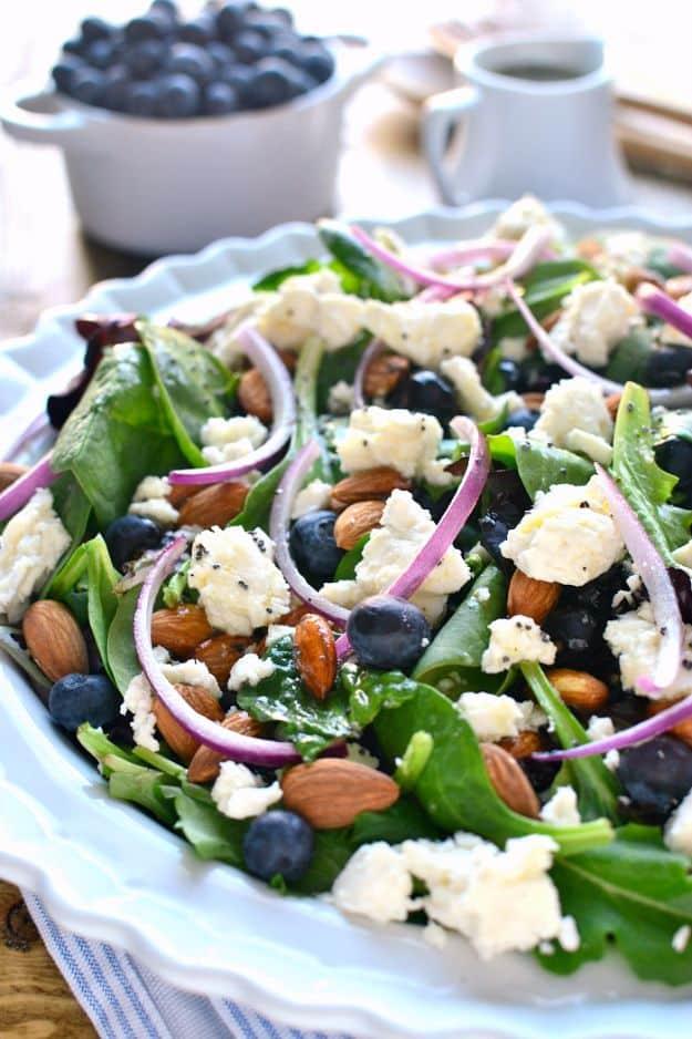 Blueberry feta salad on a white platter with mixed greens, fresh blueberries, crumbled feta, red onion and almonds