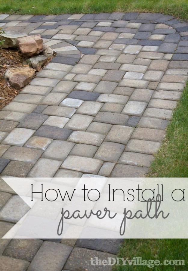 DIY curb appeal paver path in gray and tan brick laid across a lawn curving toward a stone garden edge