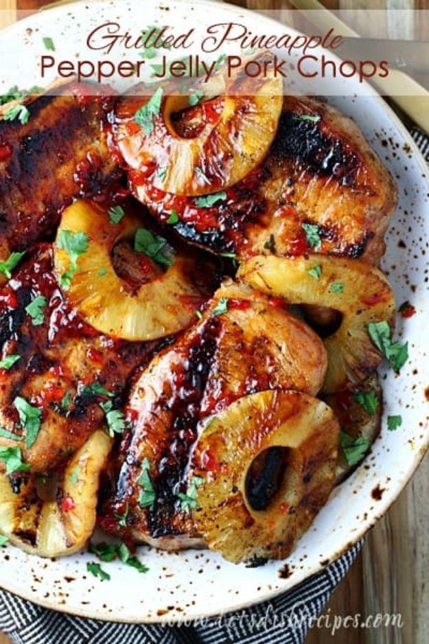 Grilled pineapple pepper jelly pork chops charred dark and served with grilled pineapple rings and cilantro