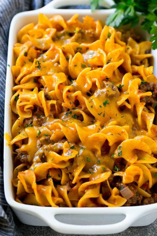 Beef noodle casserole with egg noodles in tomato sauce under a thick layer of melted cheddar and parsley
