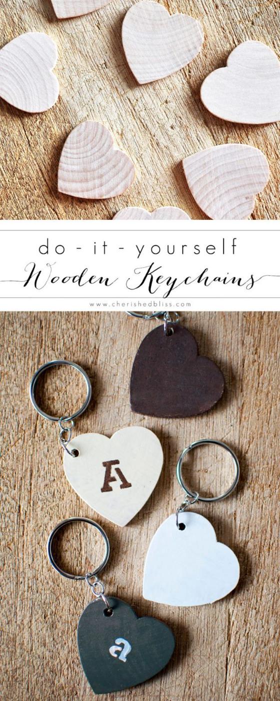 A small stained wooden heart keychain with a name stamped into the grain, hanging from a silver ring against pale wood.
