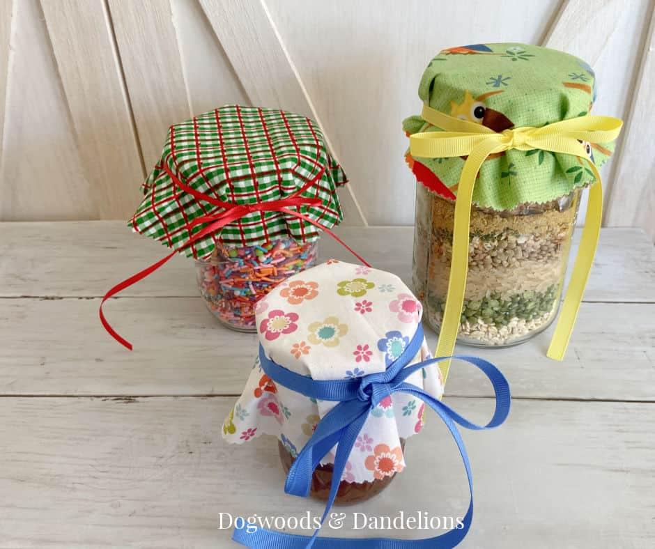 Mason jars topped with round fabric covers in small floral prints, tied at the neck with string and twine