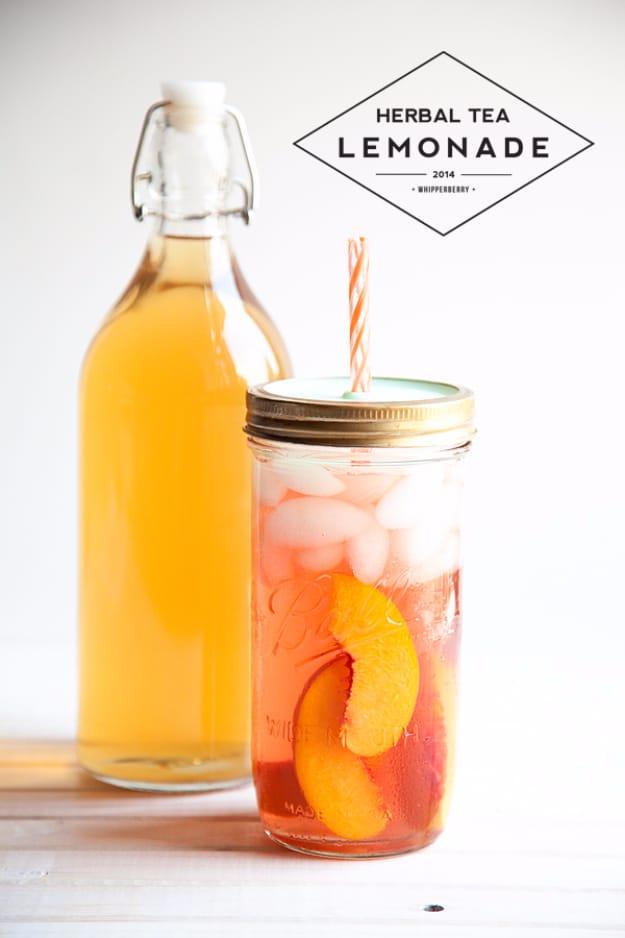 A swing top bottle of amber herbal tea beside a jar of iced tea lemonade with peach slices and a straw