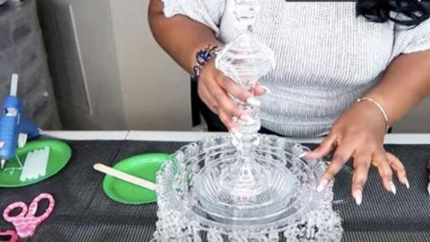 Person at a craft table pressing together stacked pressed glass bowls and lids to build a table chandelier
