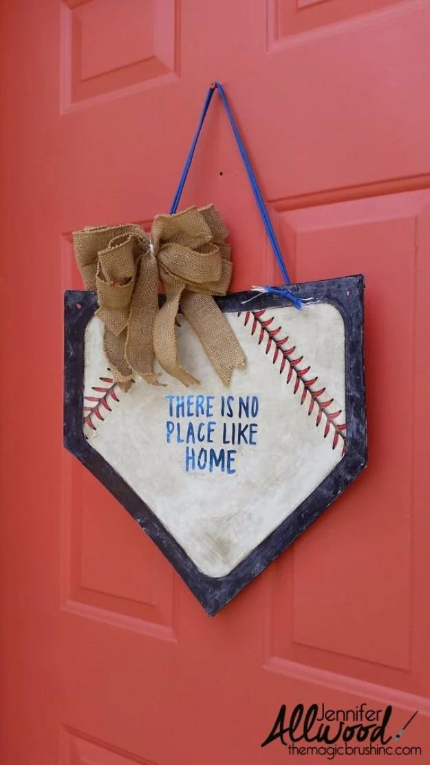 Home plate door hanger with a dark edge, red baseball stitching and There is no place like home, with a burlap bow