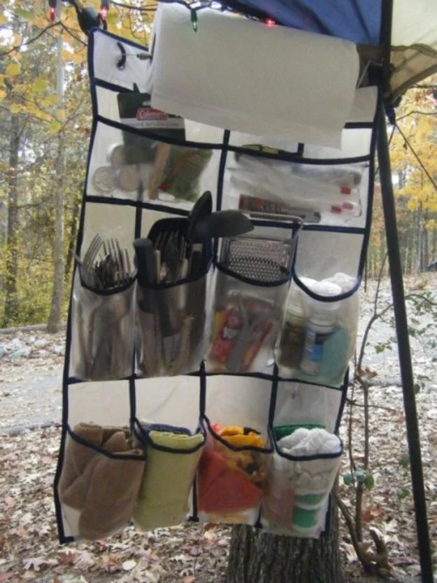 Camp kitchen organizer, a hanging shoe holder of utensils and supplies rigged to a canopy frame in the woods