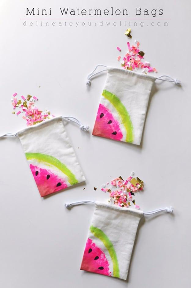 Three small white canvas drawstring bags painted with pink and green watermelon slices, scattered with confetti
