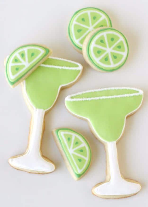 Margarita cookies iced as cocktail glasses with lime wedges and sanding sugar for salt around the rims