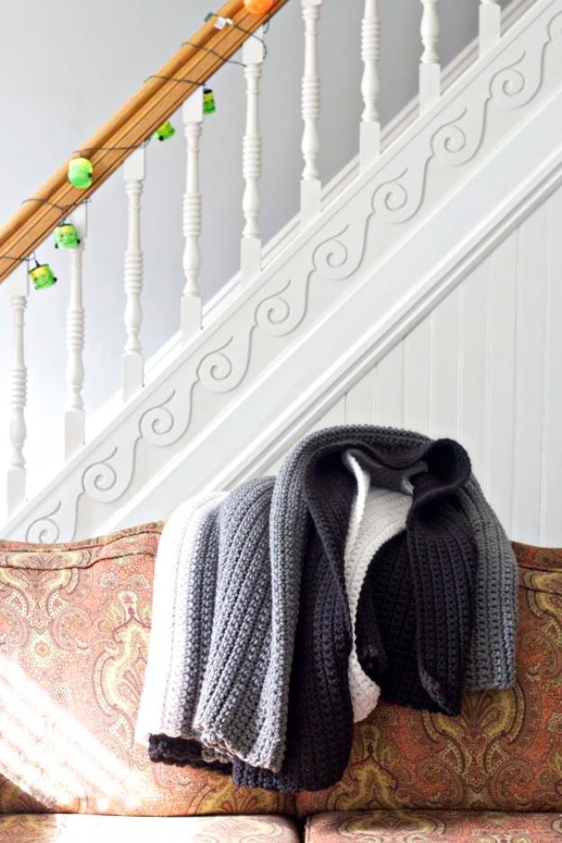 Large gray and charcoal chunky crochet blanket over a floral sofa beside a white painted staircase bannister