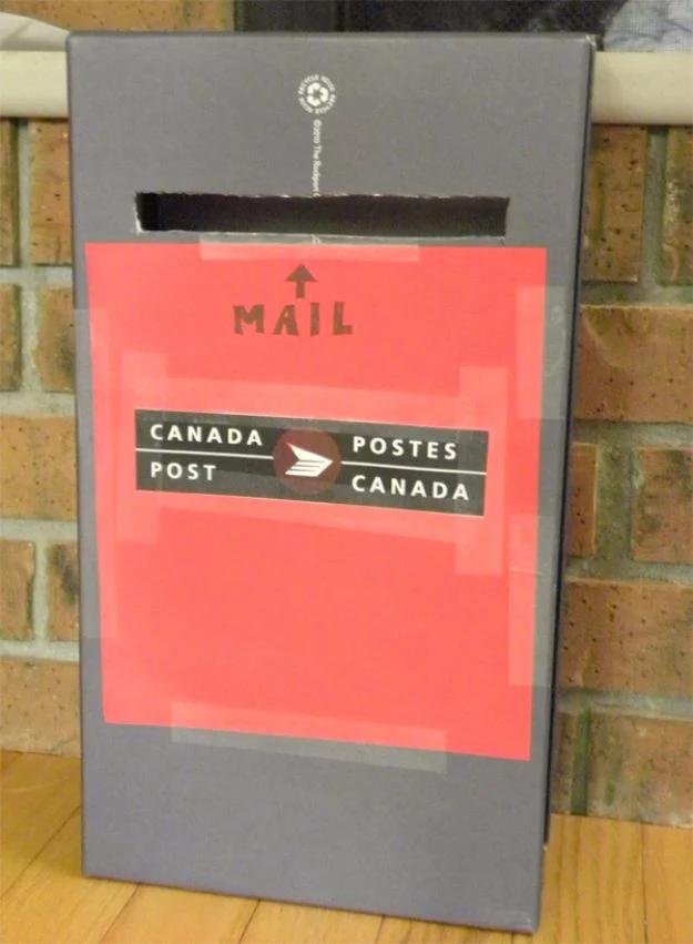 Shoe box standing on end as a play mailbox, with a letter slot, a red paper panel and a Canada Post logo