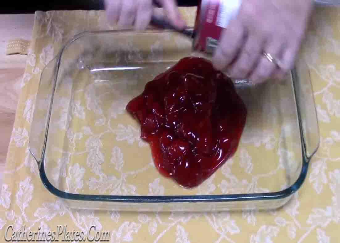 Adding the strawberry pie filling to the bottom of the baking dish