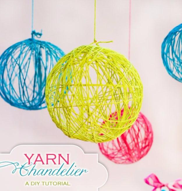 Three yarn balls in lime, turquoise and pink hanging at different heights as open hollow spheres against a pale pink wall