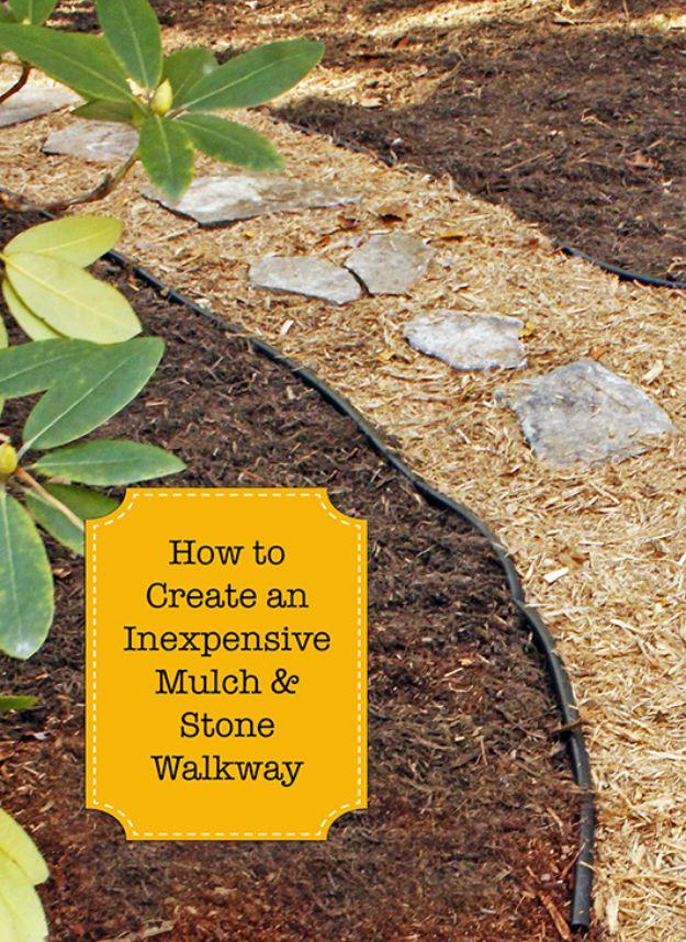 Garden path of pale flat stones set down the middle of a mulch bed, held in place by black plastic edging