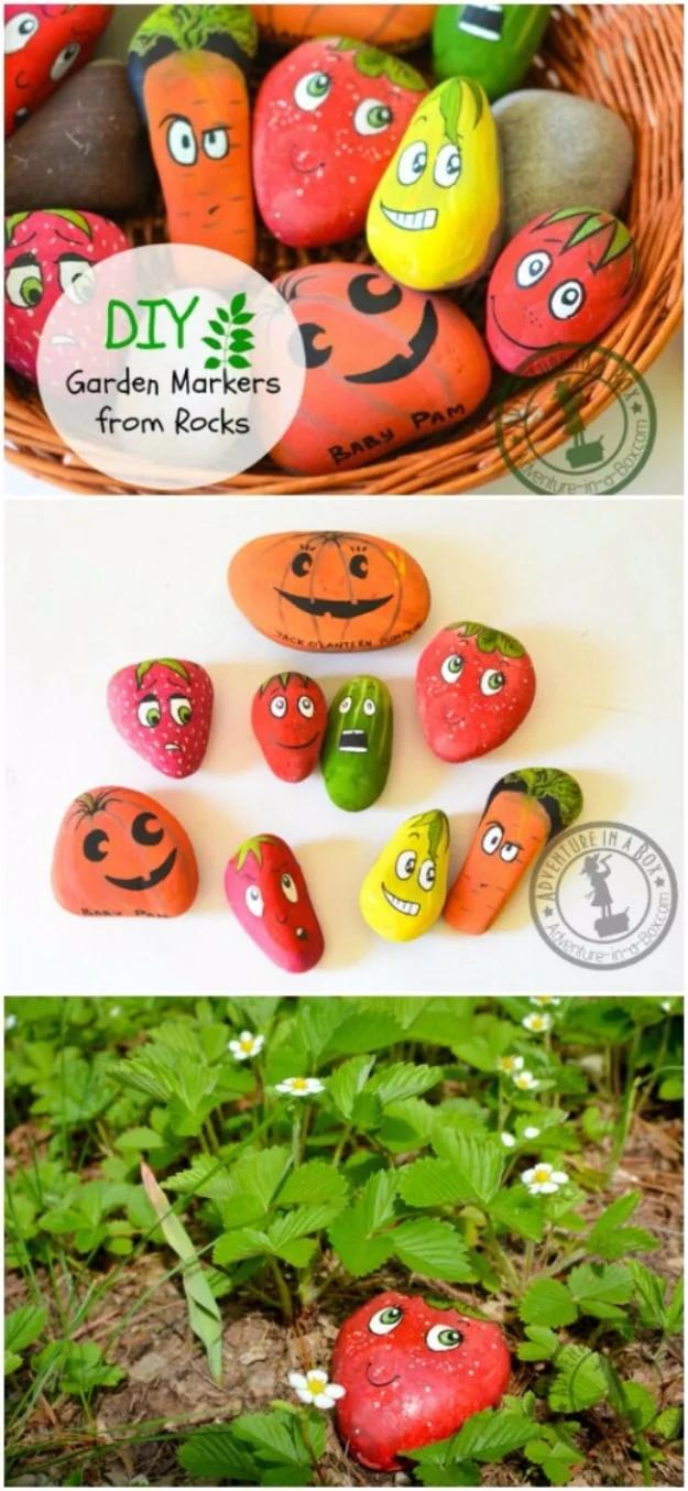 Painted rock garden markers shaped as strawberry, pumpkin, carrot and cucumber with faces, in a basket and in soil