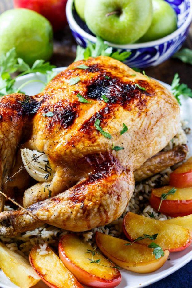Apple cider glazed roasted chicken with dark burnished skin on a platter with apple wedges and green apples