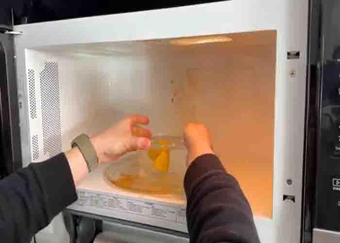 Cleaning the microwave with a bowl of vinegar and lemon