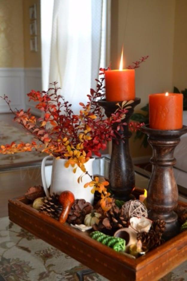 Thanksgiving centerpiece built on a burlap lined wooden tray with a pitcher, candlesticks, pine cones and gourds