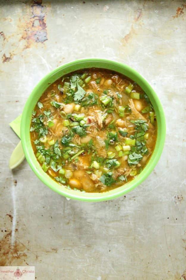 Green pork chili verde with sweetcorn and cilantro in a bright green bowl on a scratched metal surface