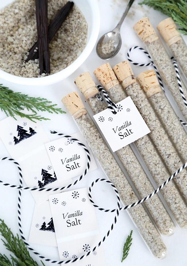 Corked glass test tubes of vanilla speckled grey sea salt with Vanilla Salt tags on black and white twine by a bowl of salt