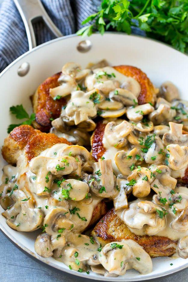 Boneless chops simmering in a creamy brown mushroom sauce with chopped parsley in a stainless steel pan